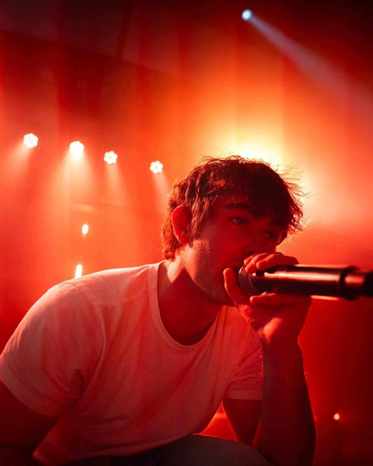 ian crouched at the front of the stage, mic up